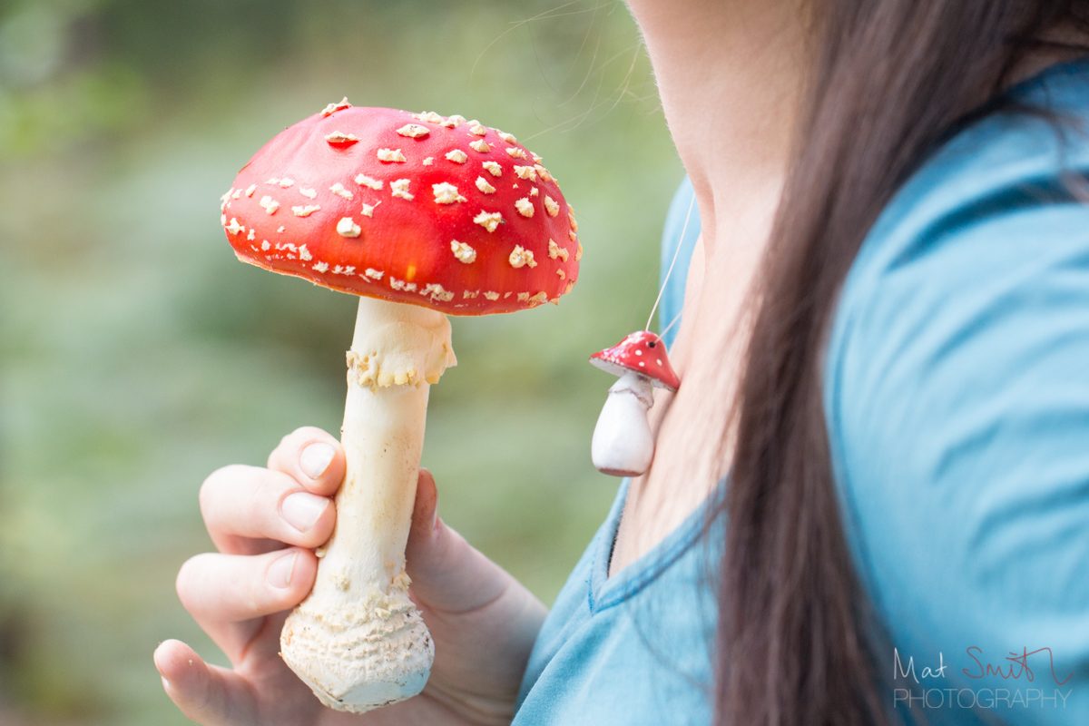 Lisa Cutcliffe wearing fly agaric jewellery beside a fly agaric, New Forest