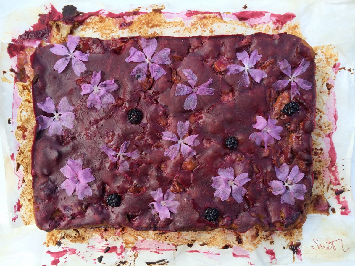 Home-baked apple and blackberry cake with elderberry icing and mallow flowers