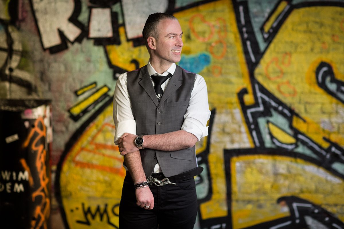 portrait of man in suit with skull and crossbones tie in shoreditch graffiti tunnel