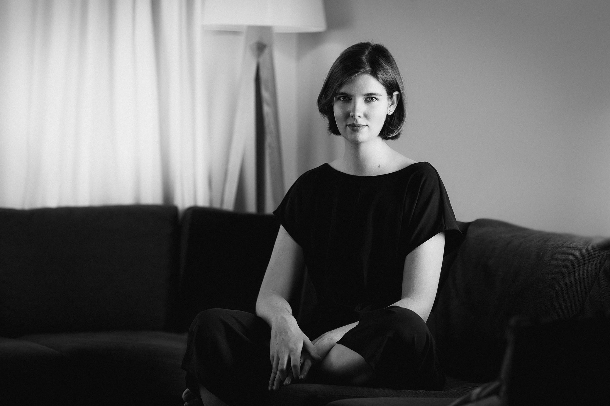 Elizabeth MacNeal, author, cross-legged on her sofa, black and white portrait by Mat Smith Photography