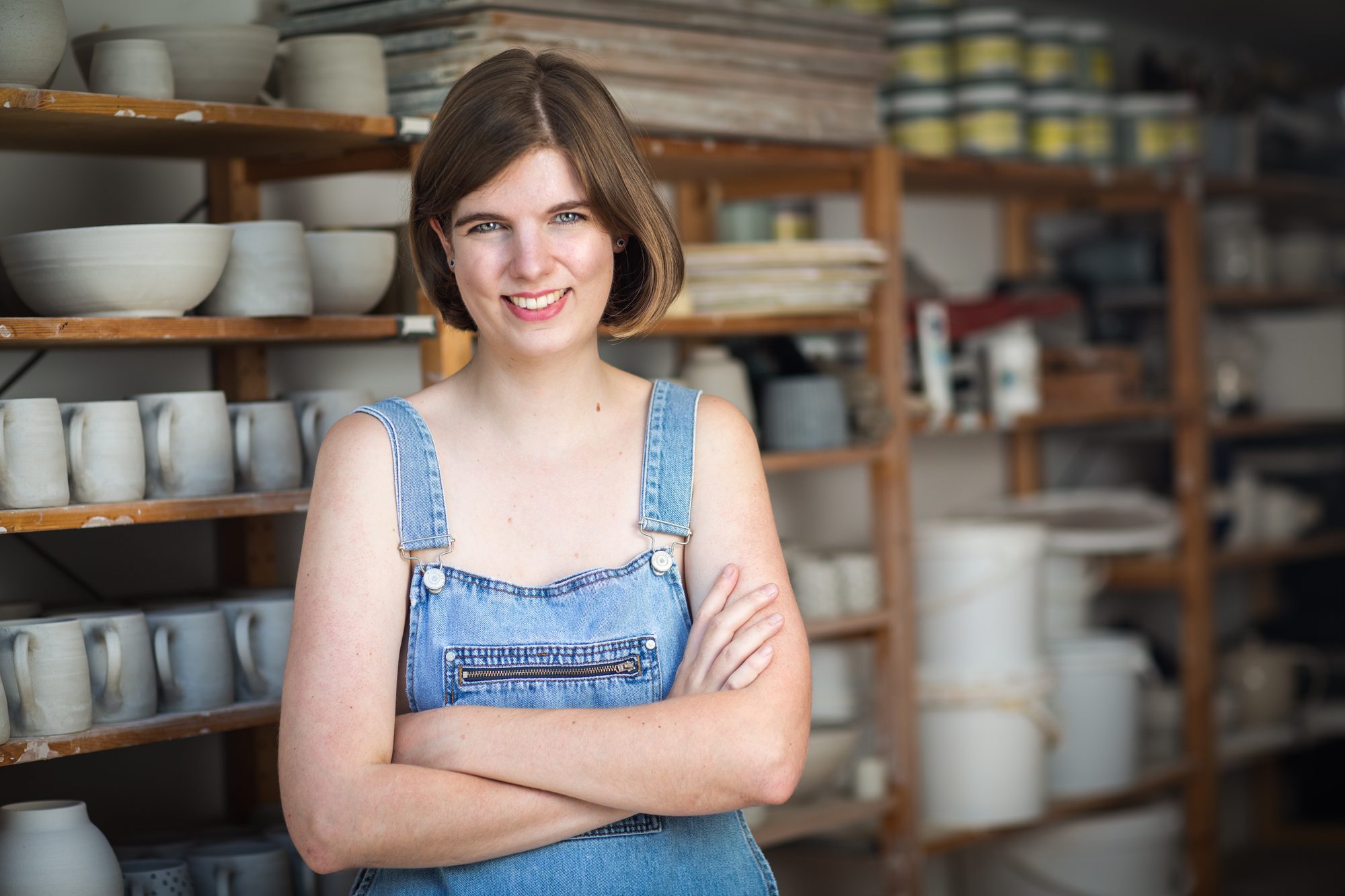 Elizabeth MacNeal, potter, in dungarees in her pottery studio, portrait by Mat Smith Photography, East London