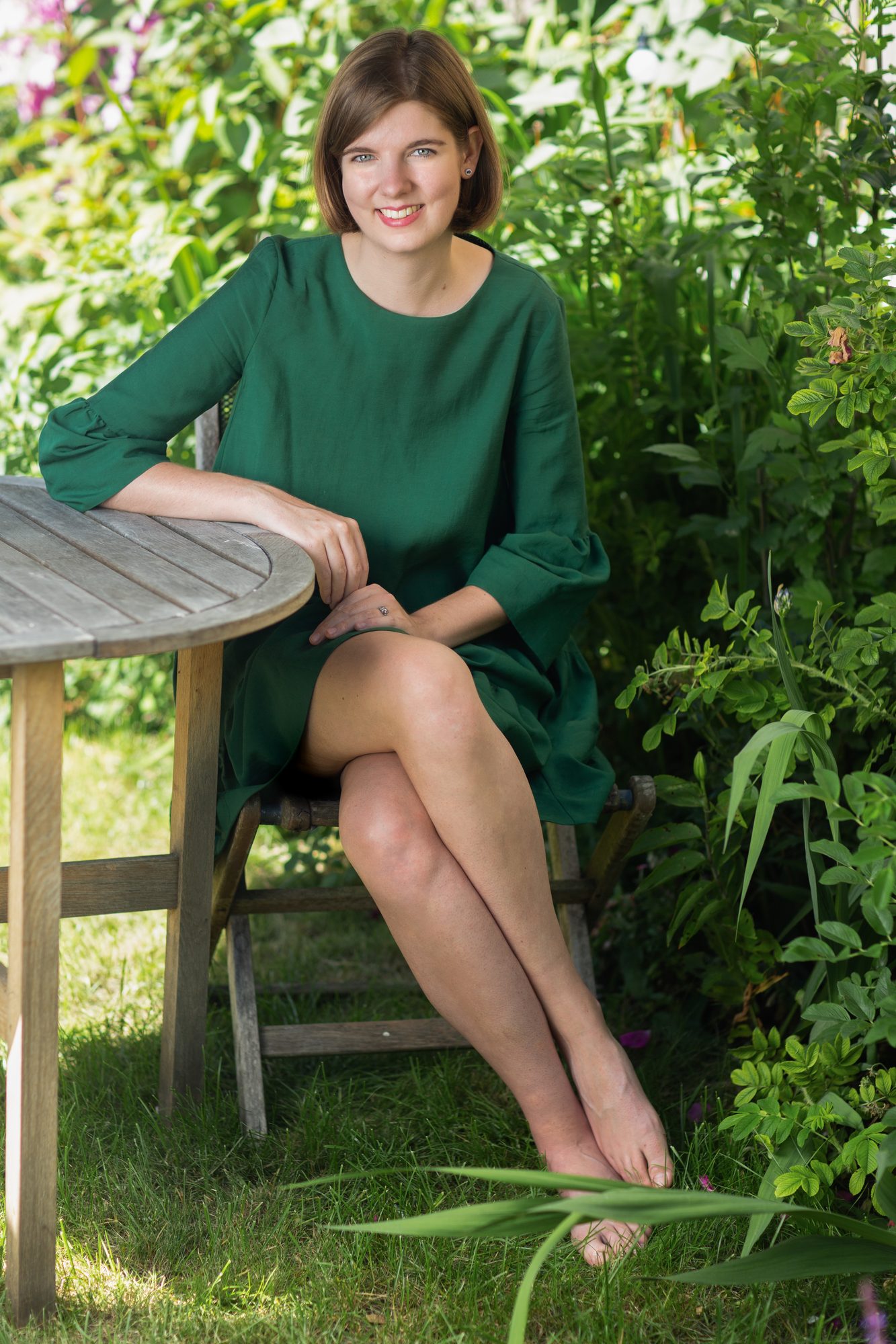 Elizabeth MacNeal, author, cross-legged under a garden umbrella, portrait by Mat Smith Photography, East London