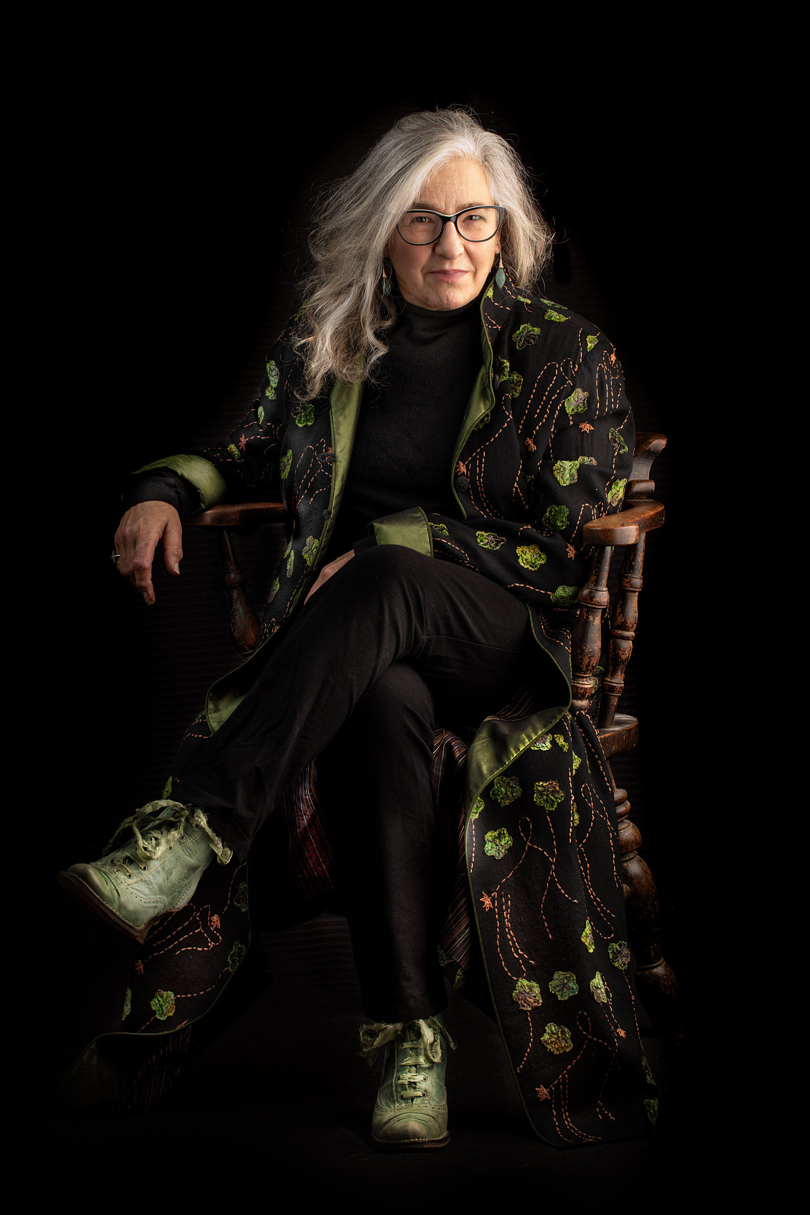 Karen Liebreich MBE, author and historian, seated in a green embroidered coat, portrait by Mat Smith Photography, Chiswick