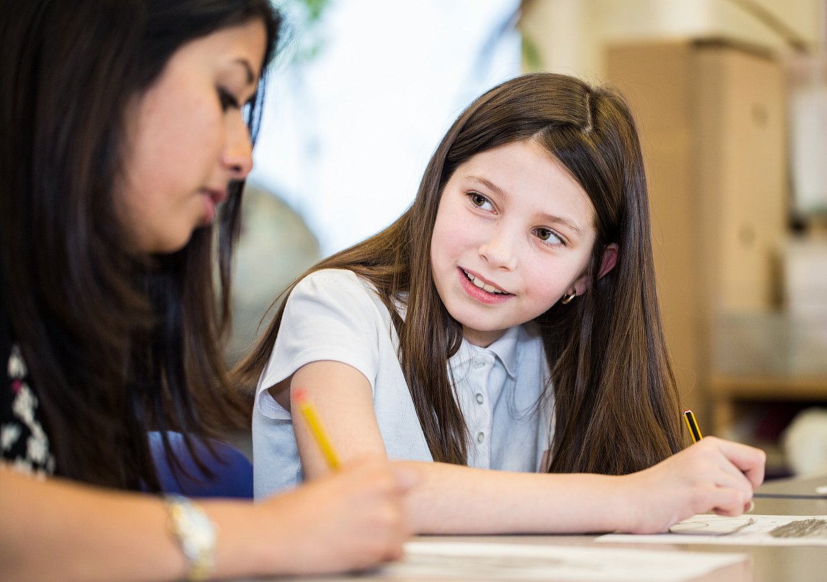 Smiling schoolgirl with her teacher in a classroom