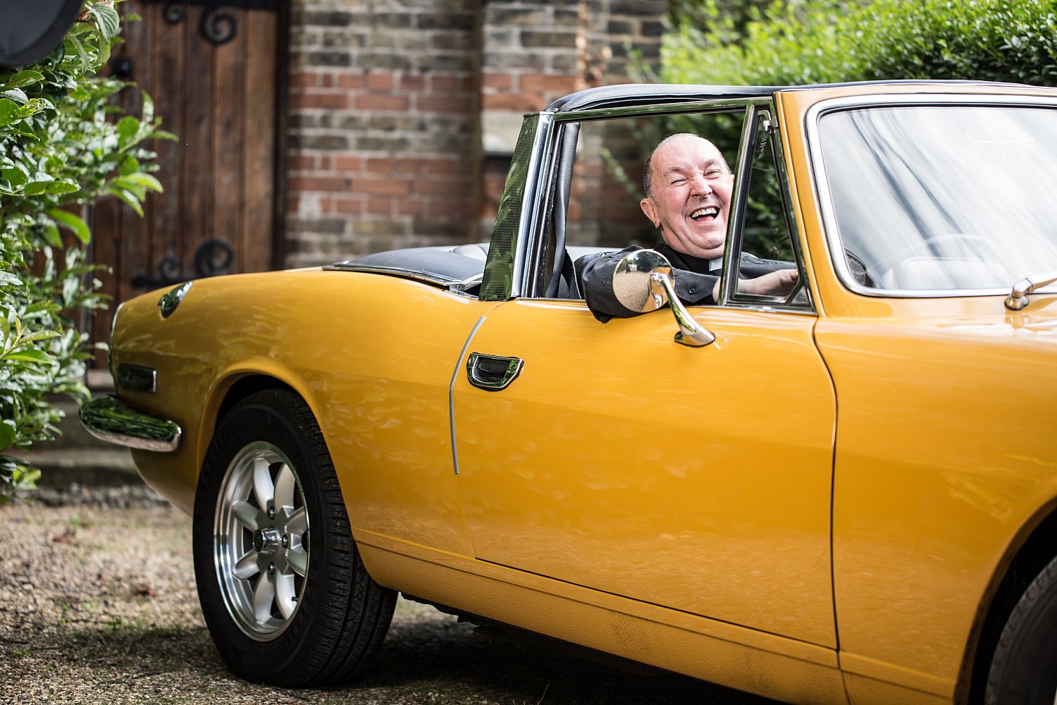 Vicar in a dog collar with a yellow convertible