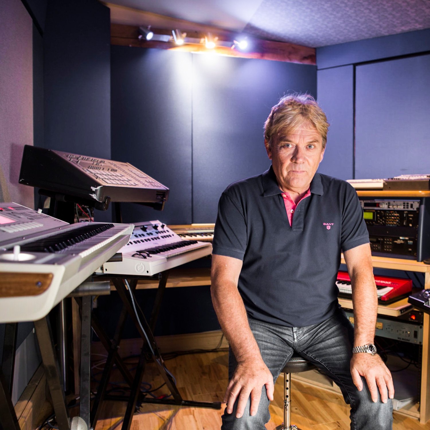 Mike Stock, songwriter and producer, seated among keyboards in a recording studio, portrait by Mat Smith Photography
