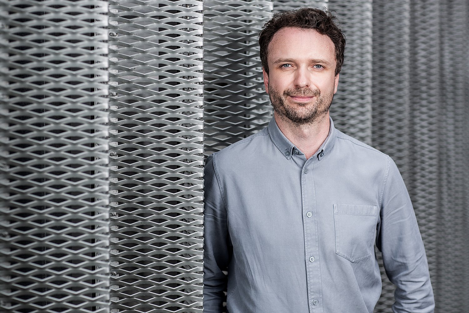 Man in a blue shirt against corrugated metal, architectural portrait in London