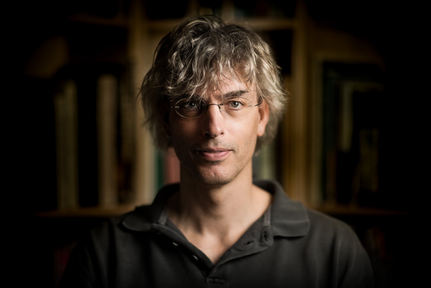 Writer in front of a bookshelf, portrait at home in London