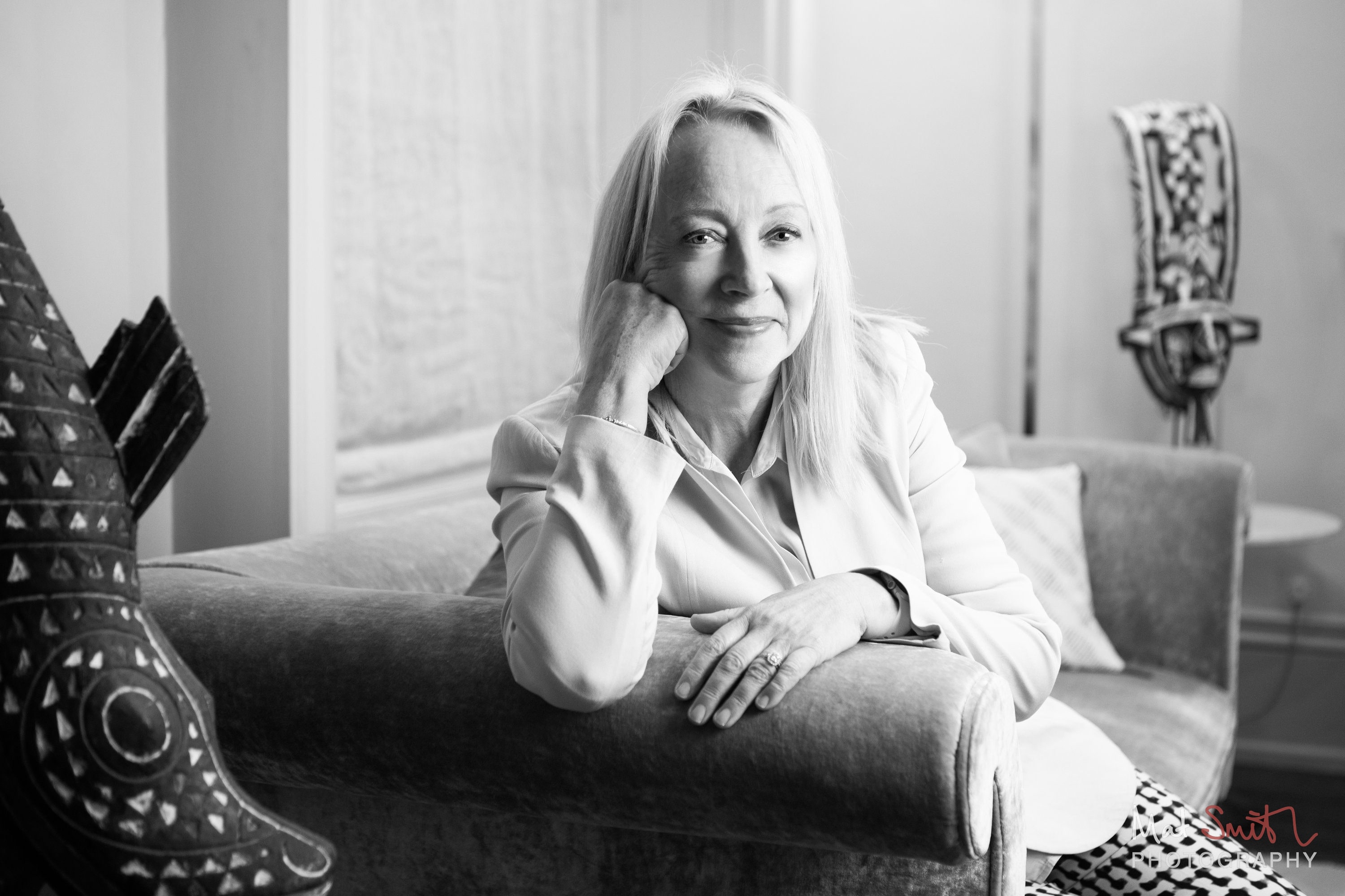 Black and white portrait of a woman leaning on a sofa arm with her chin resting on her hand, portrait by Mat Smith Photography, London
